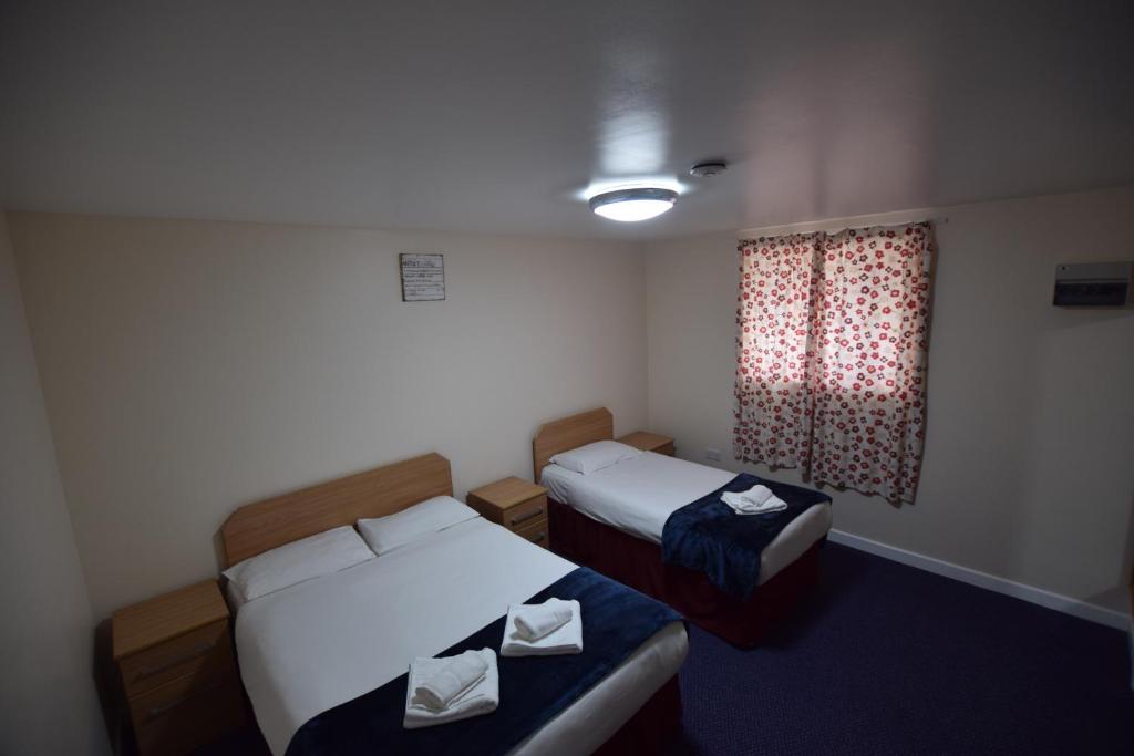 イルフォードにあるウッドランズ ロッジ イルフォードのベッド2台と窓が備わるホテルルームです。
