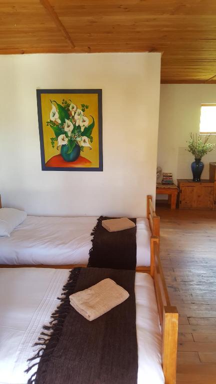 a room with two beds and a vase of flowers at Barrydale Accommodation, Backpackers in Barrydale