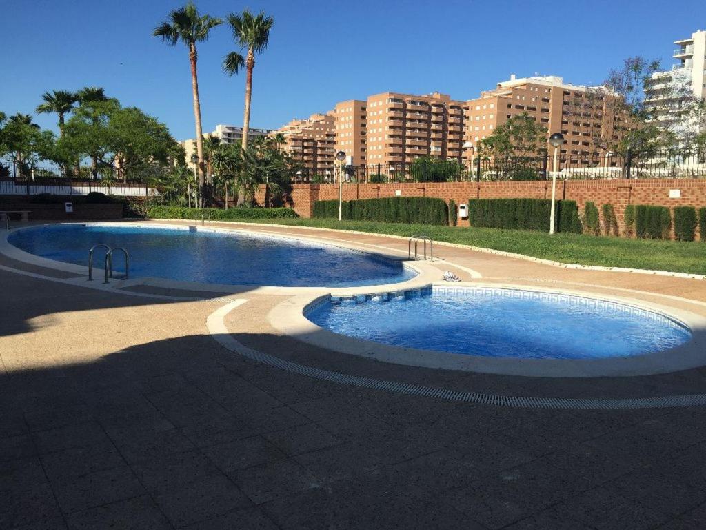 une piscine dans un parc avec des bâtiments en arrière-plan dans l'établissement APCOSTAS - Marina Mar 1a Línea, à Oropesa del Mar