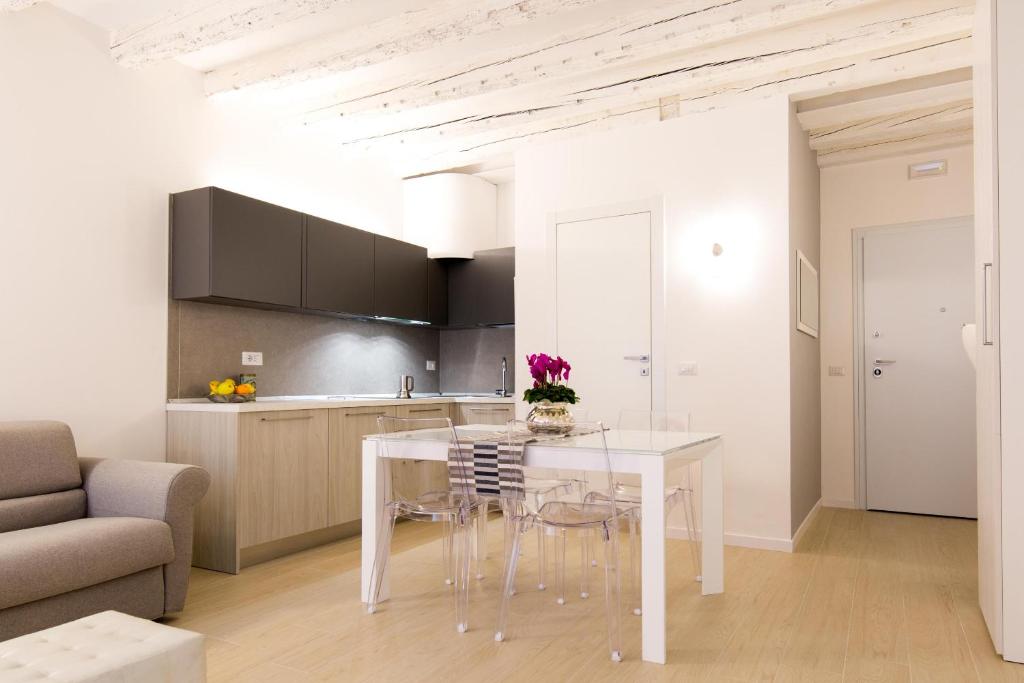 una cucina e una sala da pranzo con tavolo e sedie bianchi di " CASA SAVONAROLA " centro storico a Padova