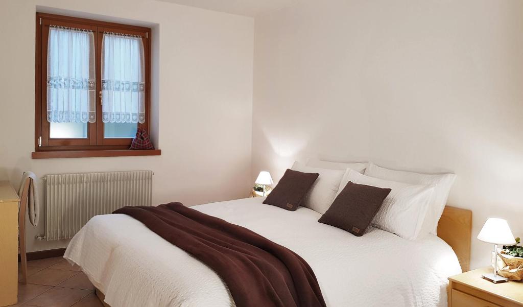 a bedroom with a white bed with two pillows at Etrusca Polsa in Brentonico