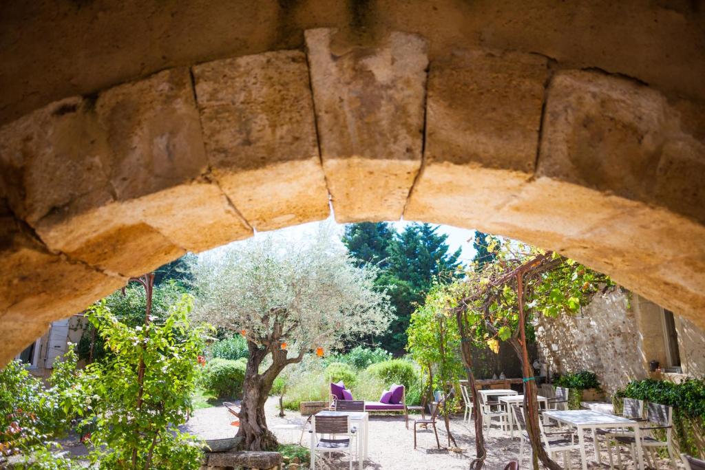a stone archway with tables and chairs in a garden at Apres La Sieste in Saint-Laurent-des-Arbres