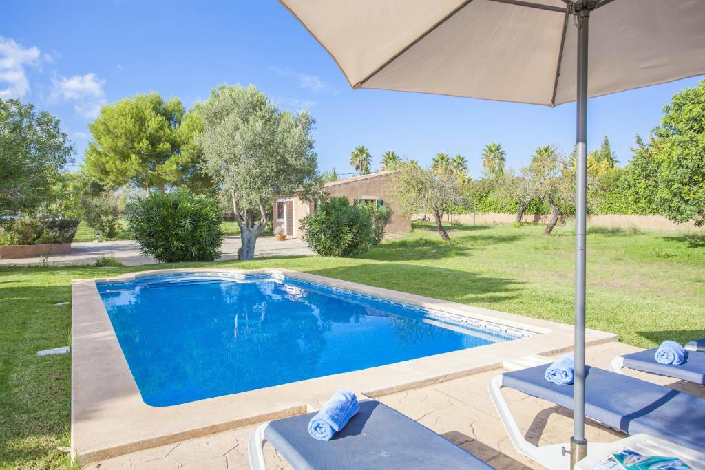 a swimming pool with an umbrella and two lounge chairs next to it at Can Andreu in Capdepera