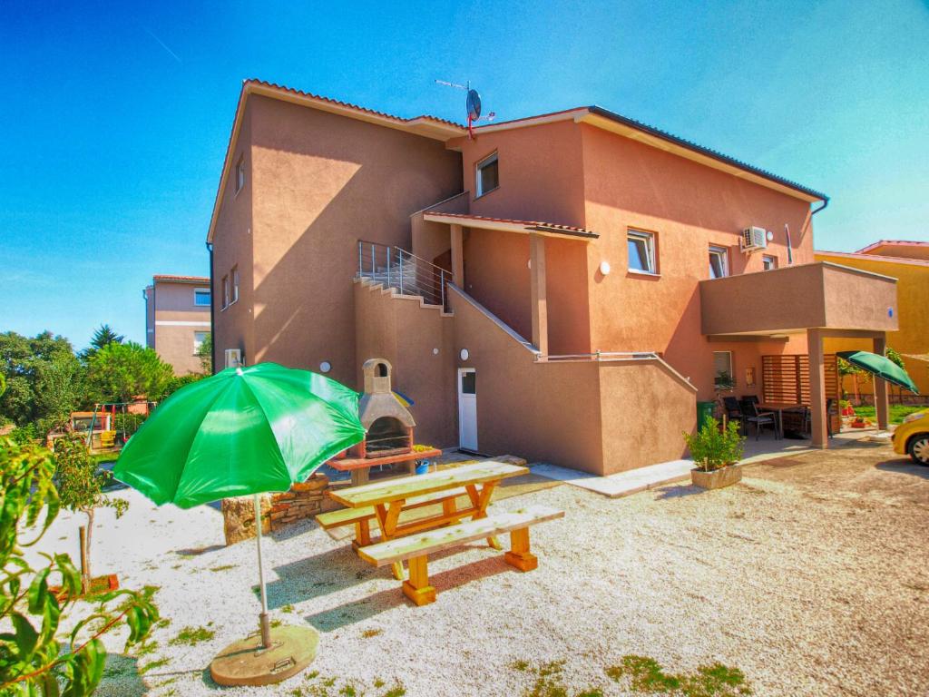 a house with a green umbrella and a picnic table at Apartments Biljana 1480 in Ližnjan