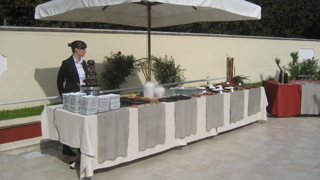 kobieta stojąca obok stołu z jedzeniem w obiekcie Hotel Ginevra w mieście Poggiomarino