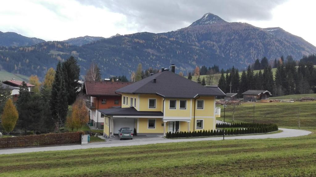 a yellow house with a mountain in the background at Appartement Grießenkareck in Flachau