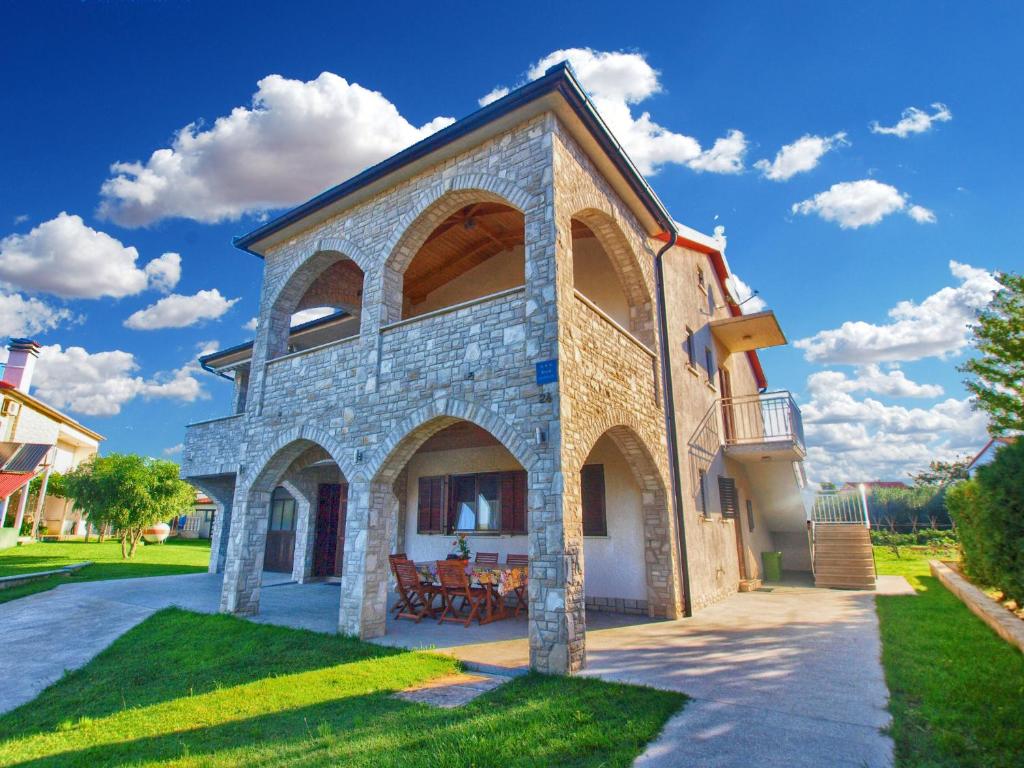 una gran casa de piedra con un banco en el césped en Apartment Luka 1481, en Medulin