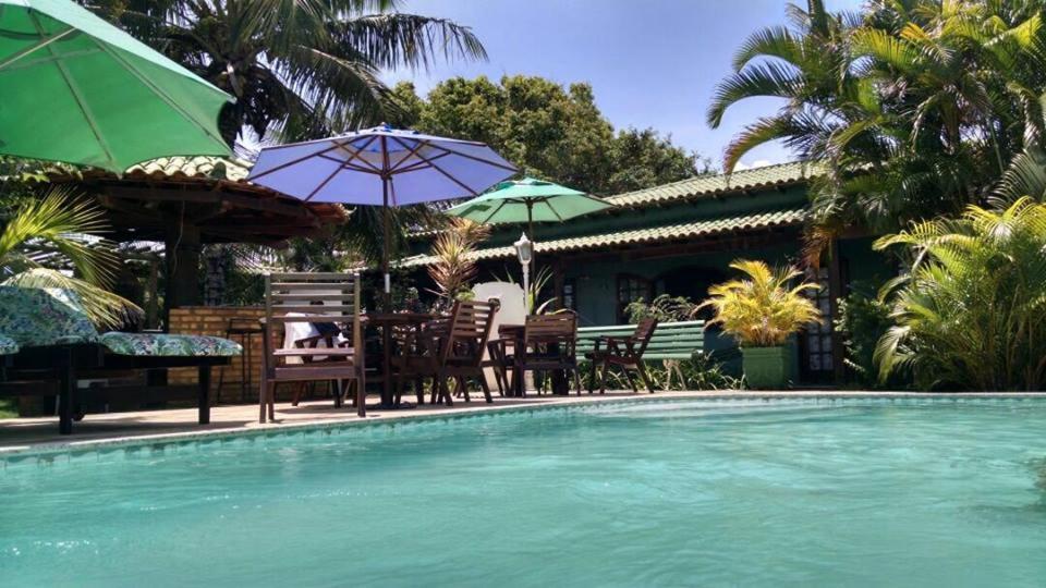 a pool with a table and chairs and umbrellas at Pousada Recanto Verde e Mar in Araruama