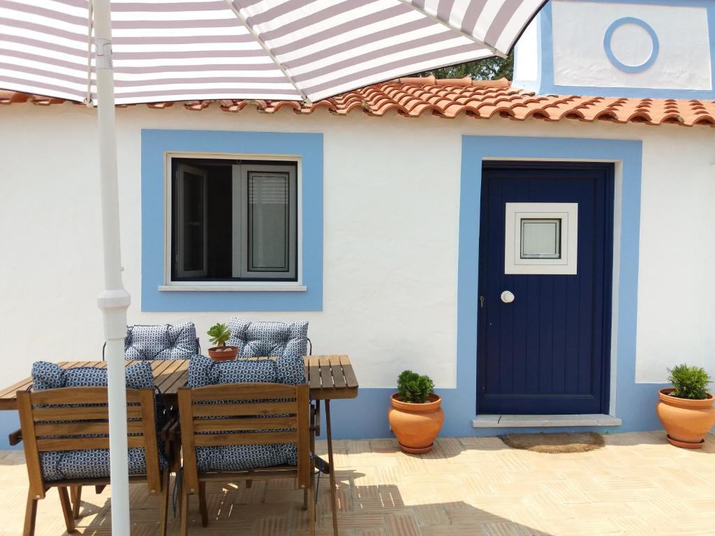 une maison avec une porte bleue et une table avec des chaises dans l'établissement Monte da Retirada, à São Luis
