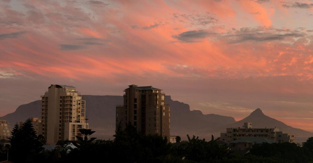a sunset with buildings and mountains in the background at Freshhh in Bloubergstrand