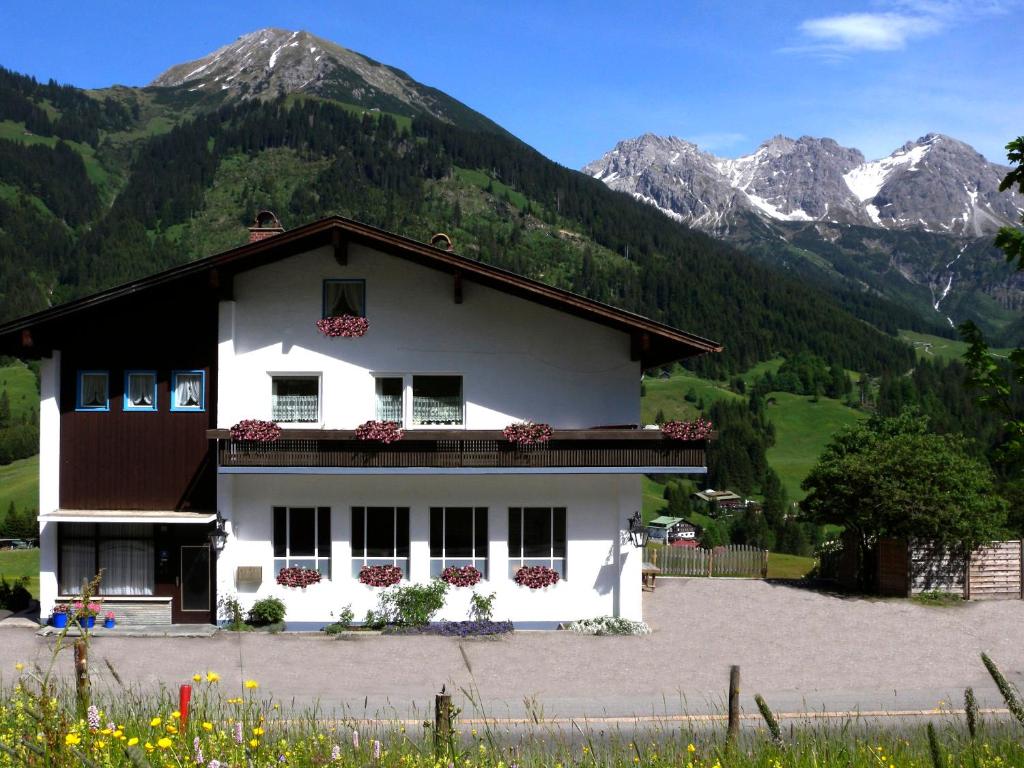 biały dom z górami w tle w obiekcie Apartmenthaus Ahorn w mieście Mittelberg