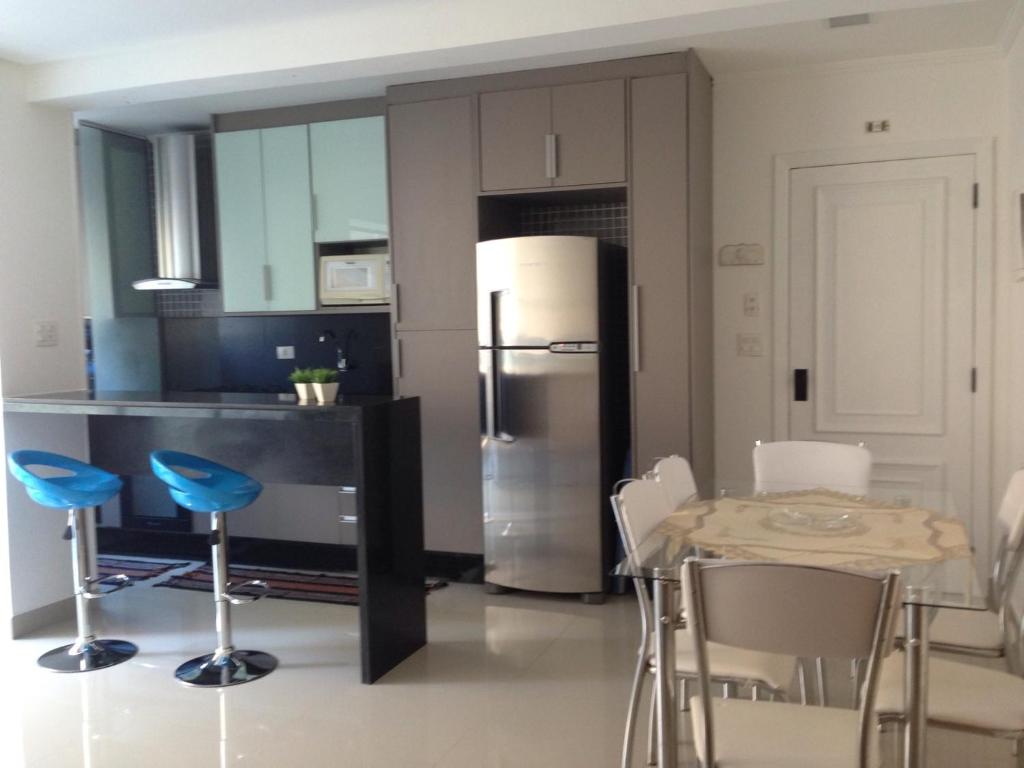uma cozinha com uma mesa e cadeiras e um frigorífico em Flat Guaruja Diferenciado no Guarujá