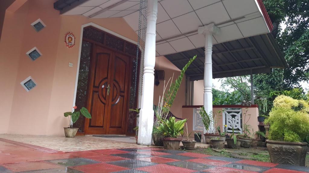 una casa con una puerta de madera y algunas plantas en Lalanga Homestay, en Kandy