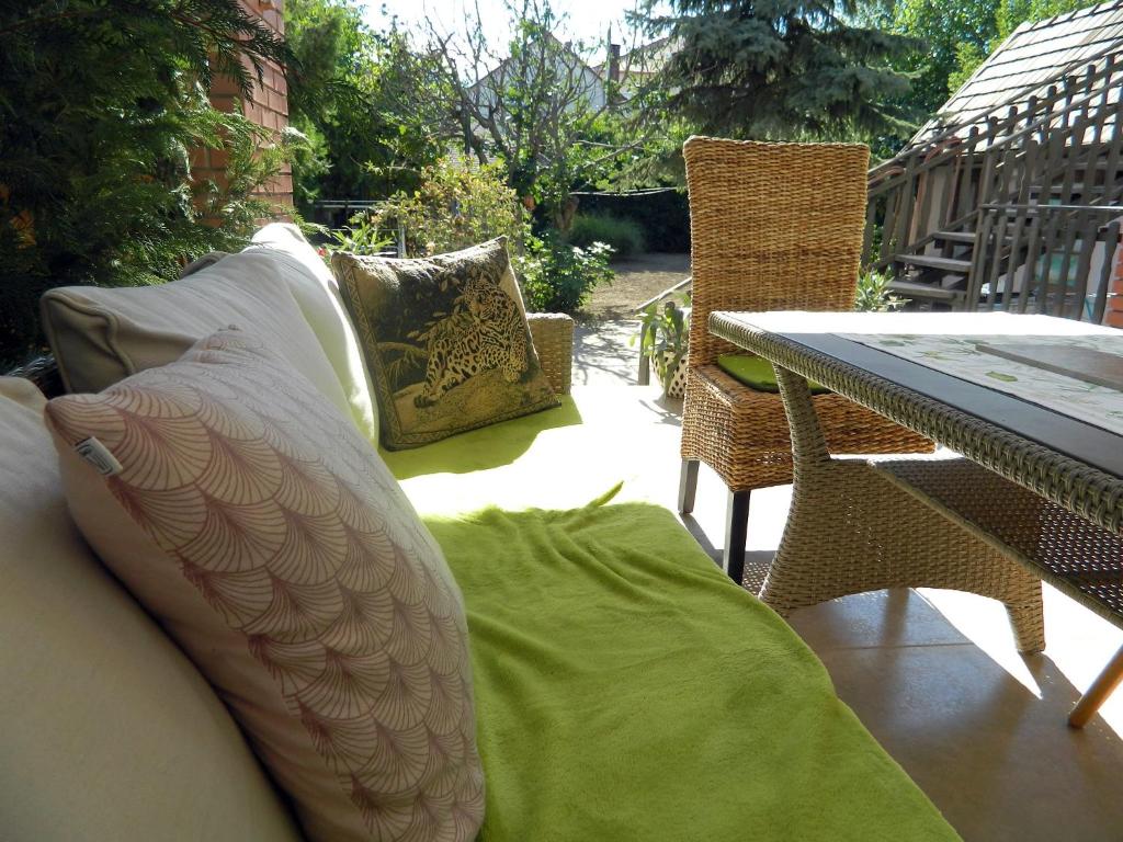 un patio con mesa, sillas y almohadas en Helga Vendégház, en Budaörs