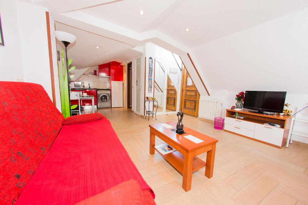 sala de estar con sofá rojo y TV en Apartamentos Madrid Centro, en Madrid