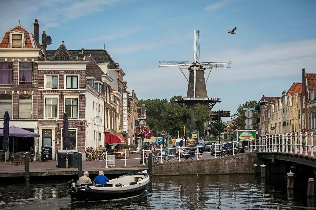 twee mensen in een boot in een kanaal met een windmolen bij City Hotel Rembrandt in Leiden