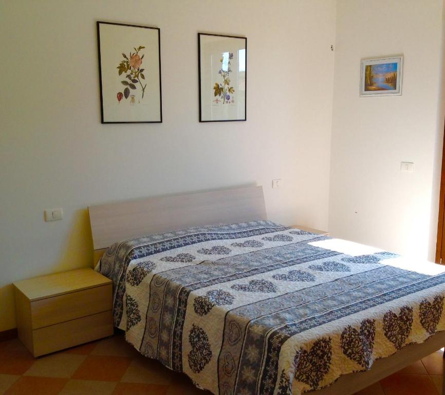 サンタンブロージョ・ディ・ヴァルポリチェッラにあるPaola Apartmentsのベッドルーム1室(ベッド1台付)が備わります。壁に2枚の写真が飾られています。