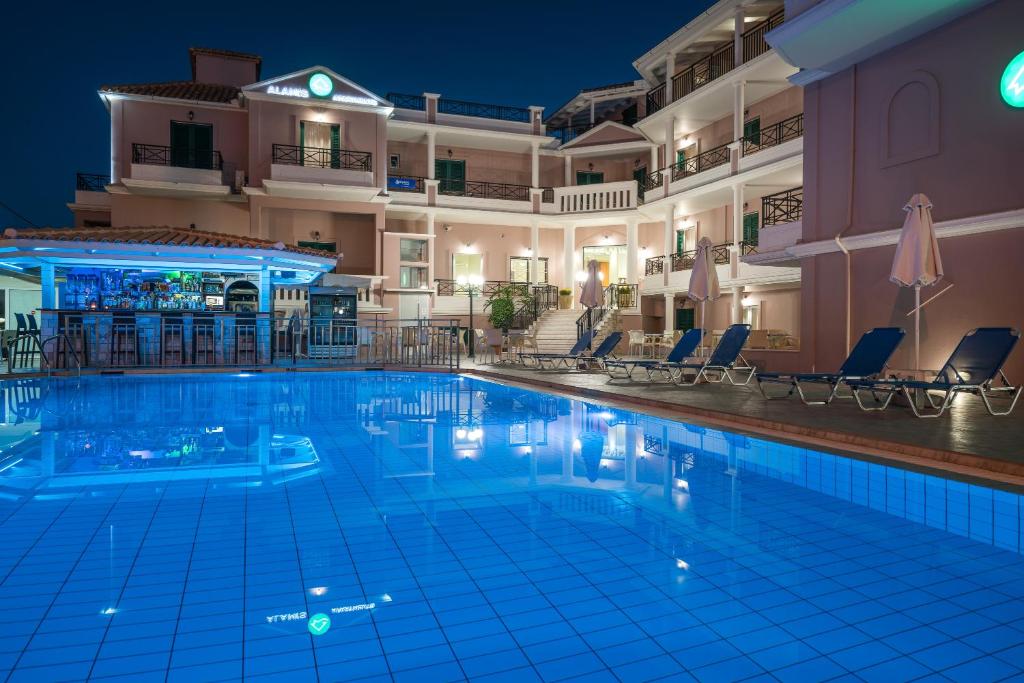 a swimming pool in front of a hotel at night at Alamis Hotel & Apartments in Tsilivi