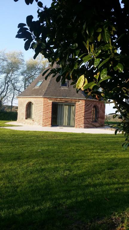 una casa de ladrillo con una ventana en un campo de hierba en Le Manège en Varengeville-sur-Mer