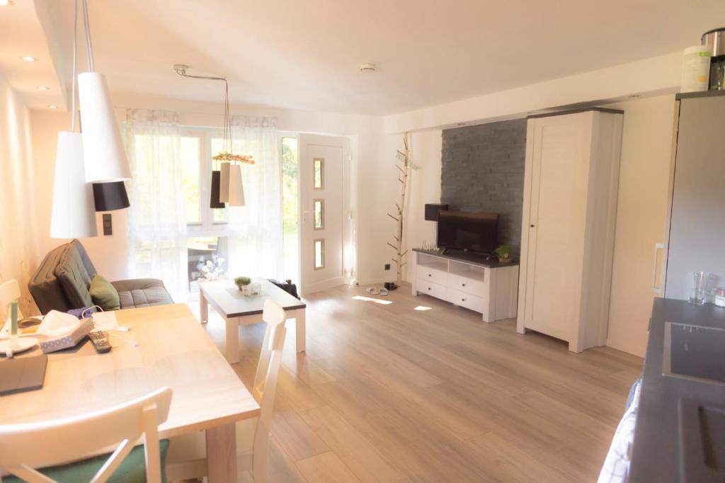ein Wohnzimmer mit einem Tisch und ein Wohnzimmer mit einem TV in der Unterkunft Ferienwohnung Saalhausen Sauerland in Saalhausen