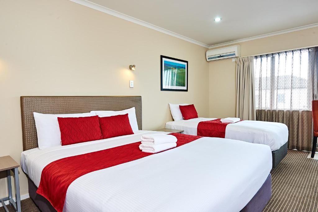 a hotel room with two beds with red pillows at Auckland Airport Lodge in Auckland