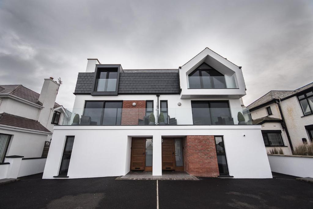 una casa blanca con techo negro en Ocean Breeze, en Portstewart