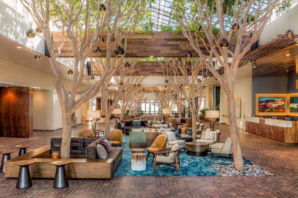 een lobby met bomen, banken en tafels bij Portola Hotel & Spa in Monterey