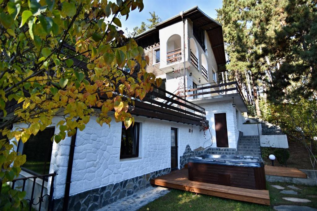 Spa Villa Galileev في فيلينغراد: منزل من الطوب الأبيض مع سطح خشبي أمامه