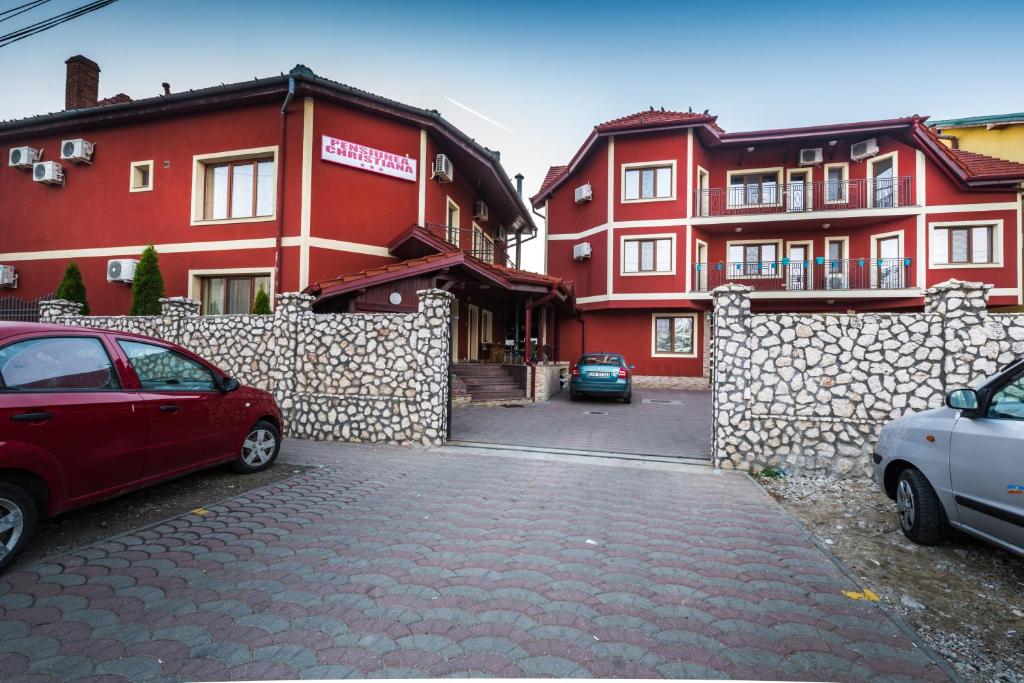 a group of red buildings with cars parked in front at Pensiunea Christiana in Arad