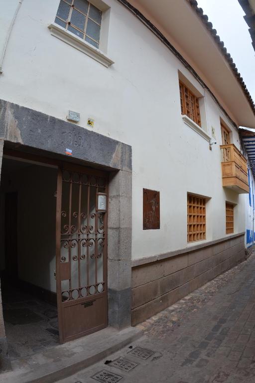 biały budynek z brązowymi drzwiami na ulicy w obiekcie Departamentos Cusco w Cuzco