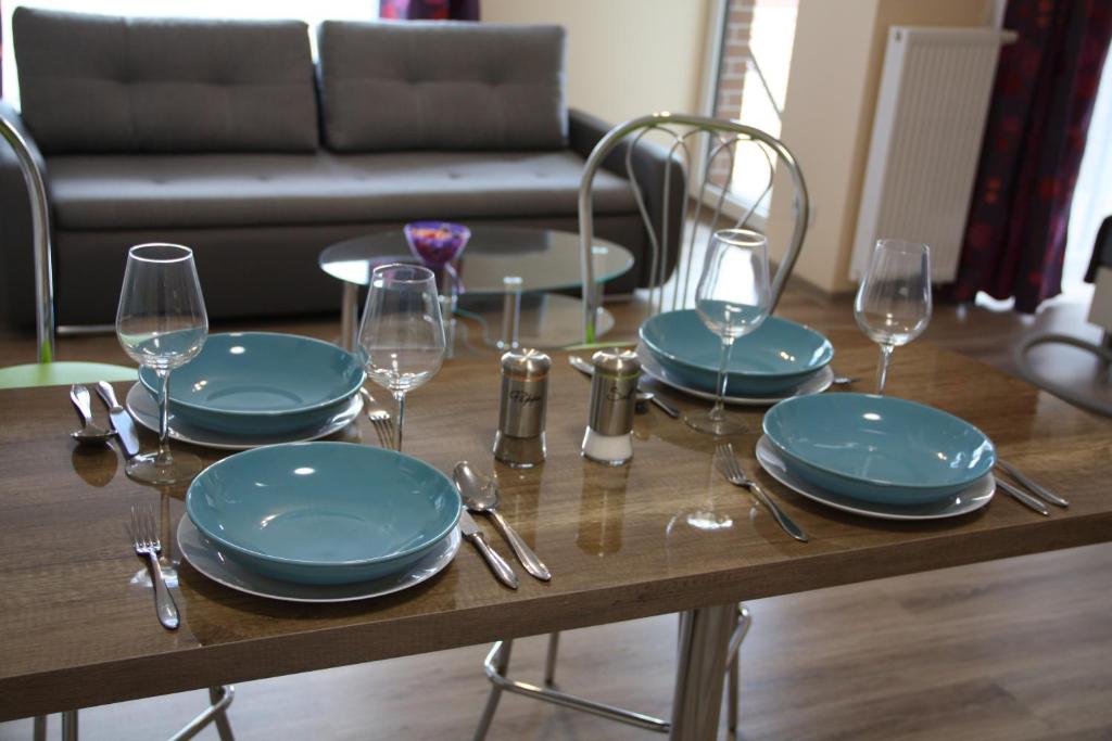 uma mesa com pratos e copos de vinho em Apartament Tabaco em Lódź