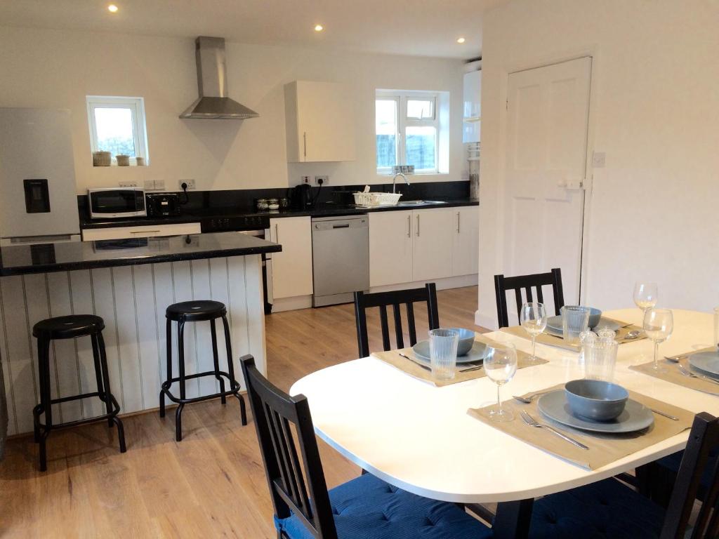 a kitchen and dining room with a white table and chairs at Avocet House in Wells next the Sea