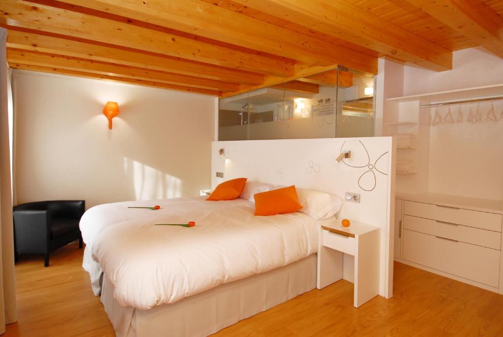 um quarto com uma cama branca e almofadas laranja em Hostal riMboMbin em Burgos