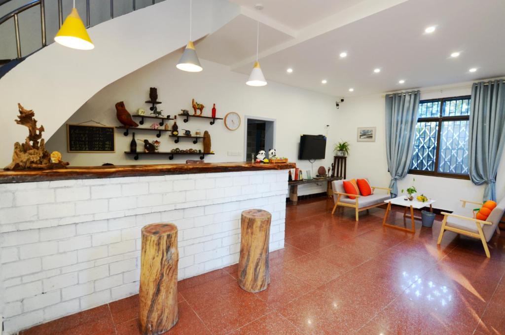 a living room with a bar and wooden stools at Peace Inn The Leshan Giant Buddha Branch in Leshan