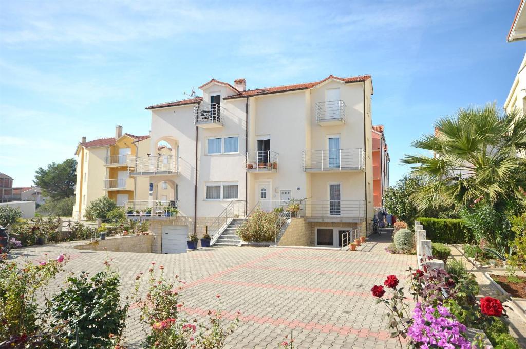 een groot wit huis met een binnenplaats met bloemen bij Apartments Mara in Vodice
