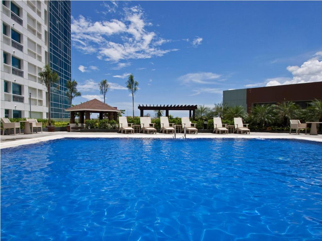 a large pool with chairs and a gazebo at Quest Serviced Residences in Cebu City