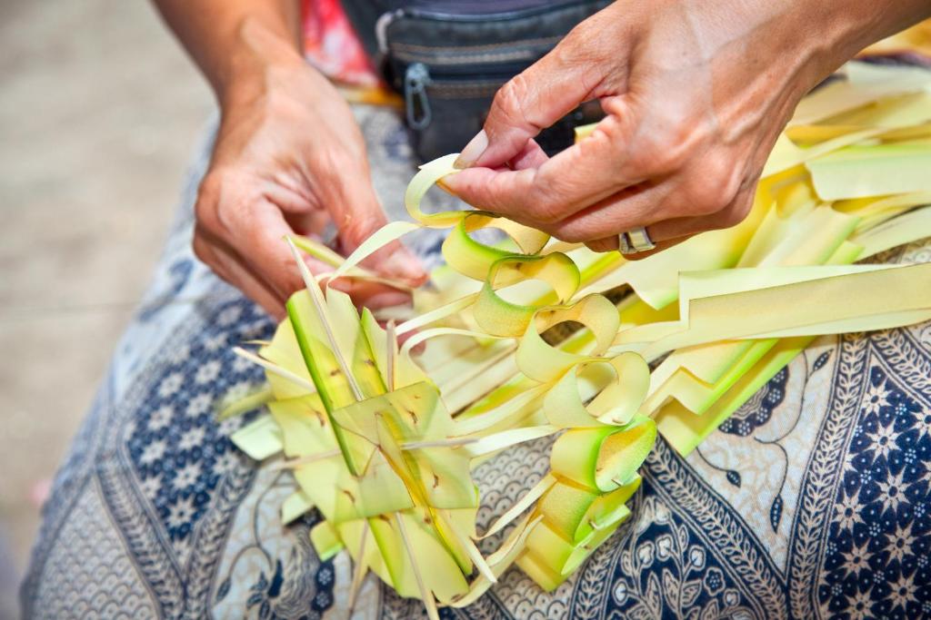 a woman is holding a bunch of fruit on her lap at Anantara Uluwatu Bali Resort in Uluwatu