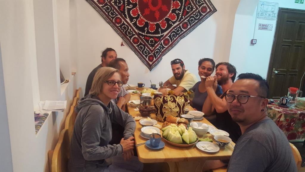 a group of people sitting around a wooden table at Amir Hostel in Samarkand