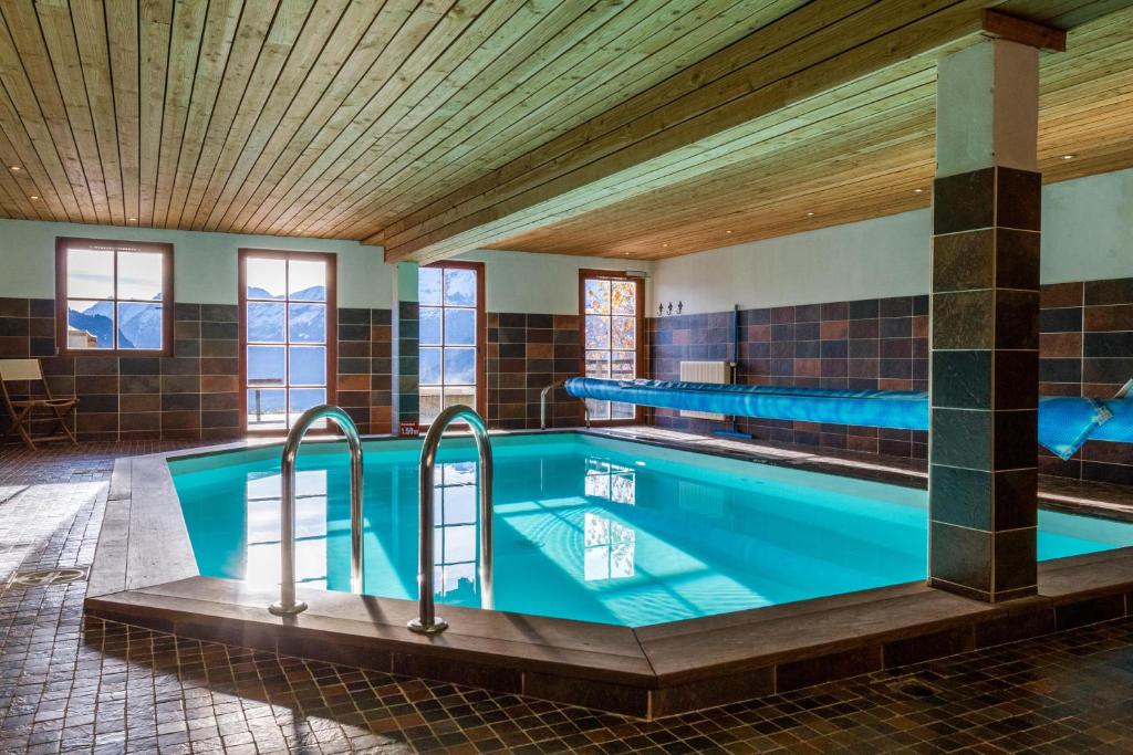 a swimming pool in a building with a tile ceiling at Chalet Il fera beau demain in Villard-Reculas