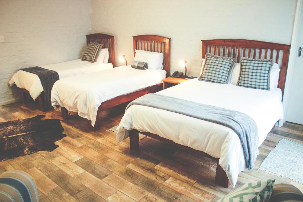 two beds in a room with wooden floors at Merino Inn Hotel in Colesberg
