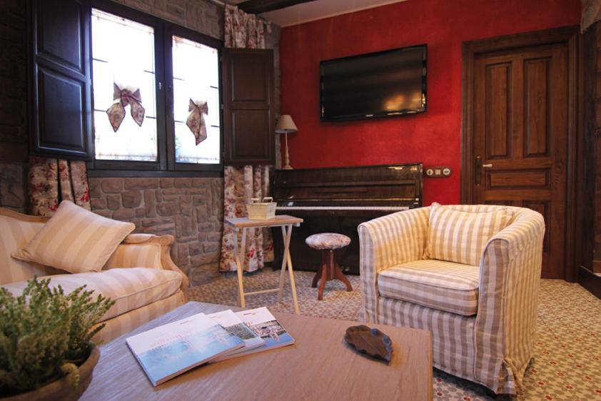 a living room with a couch and a piano at Hotel Rural La Tenada in Carcedo de Burgos