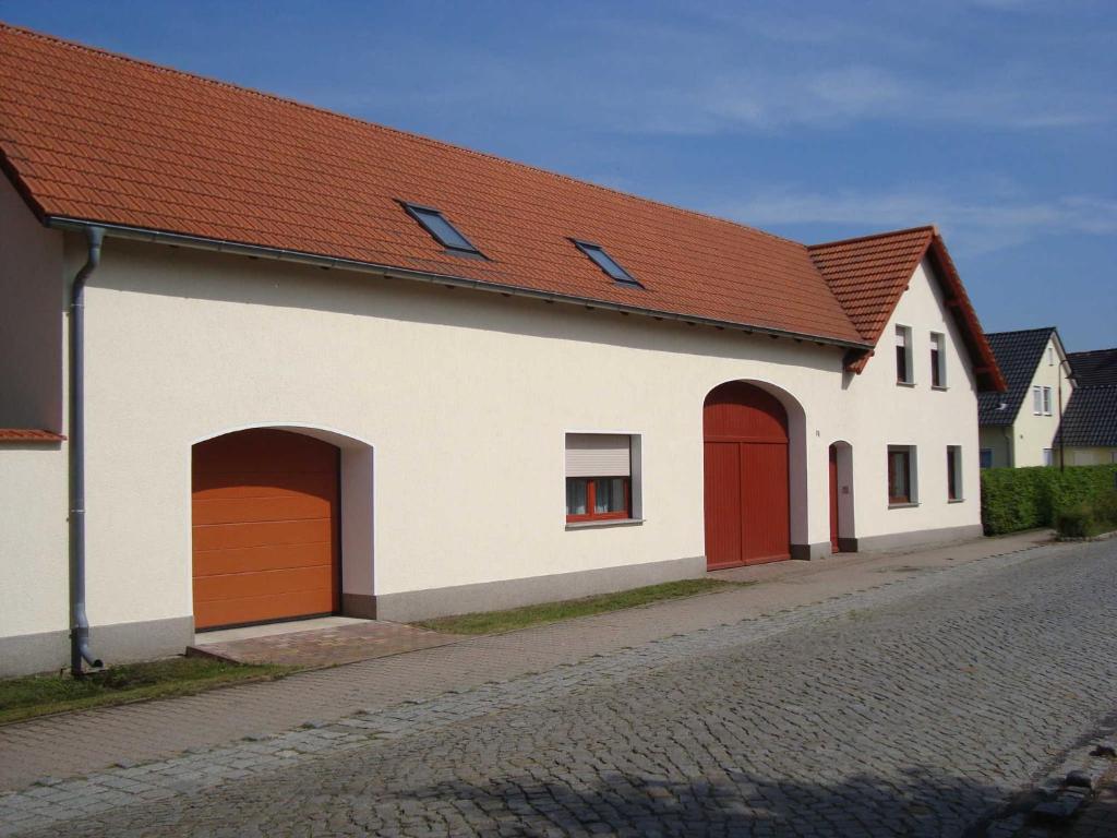 a white building with red doors on a street at Ferienwohnung Zschornack in Wittichenau