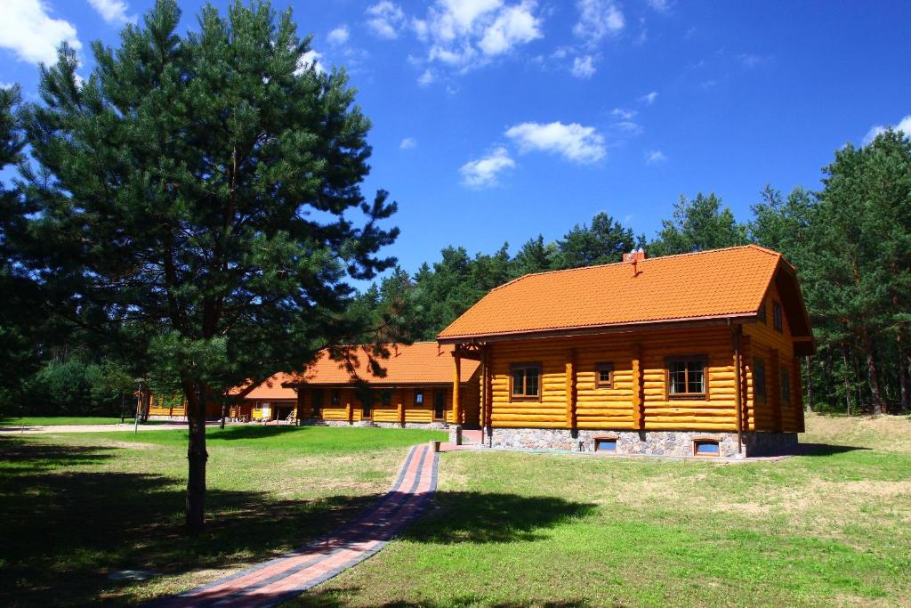 uma cabana de madeira com um telhado laranja e uma árvore em Asvejos slenis em Sužionys