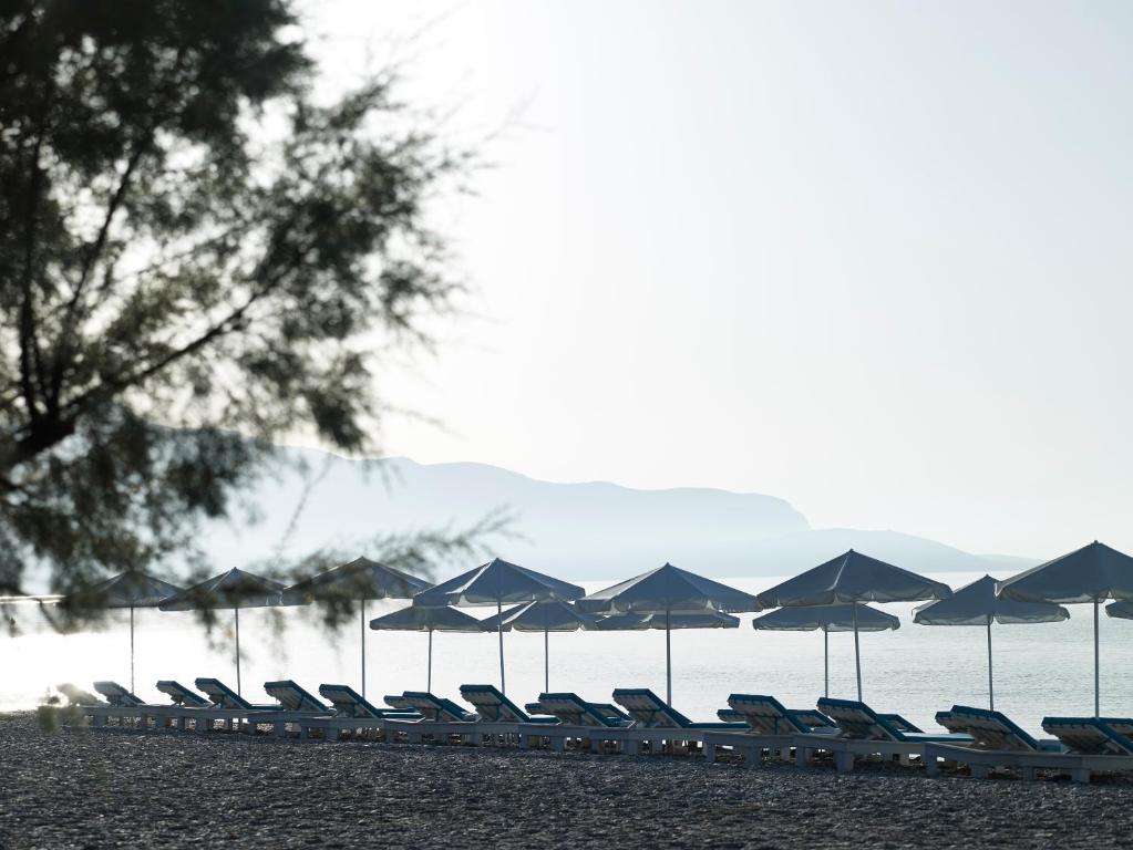 a row of chairs and umbrellas on a beach at Kouros Seasight Hotel in Pythagoreio