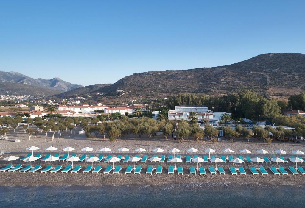 a group of umbrellas and chairs on a beach at Kouros Seasight Hotel in Pythagoreio