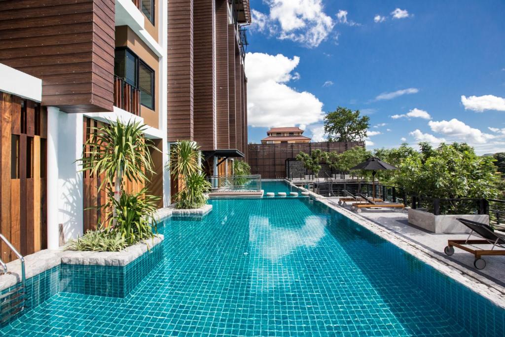 una piscina al lado de un edificio en Natee The Riverfront Hotel Kanchanaburi en Kanchanaburi