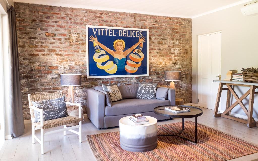 a living room with a couch and a brick wall at Petit Jourdan Cottage in Franschhoek