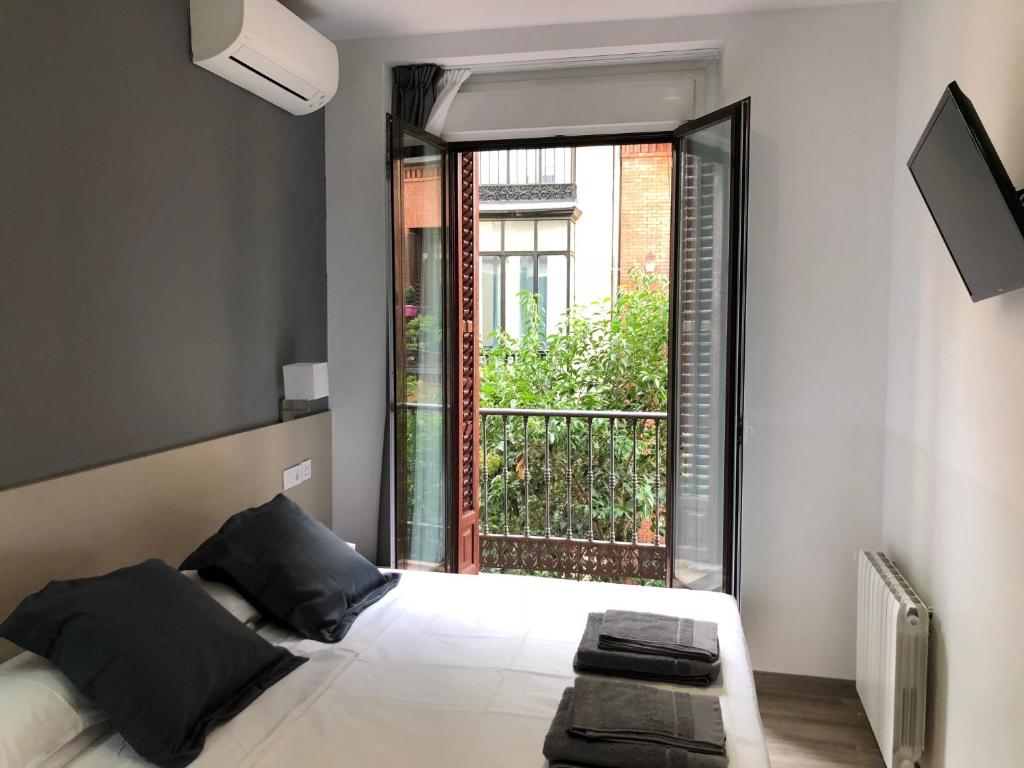 a bedroom with a bed and a large window at Hostalin Madrid Atocha in Madrid