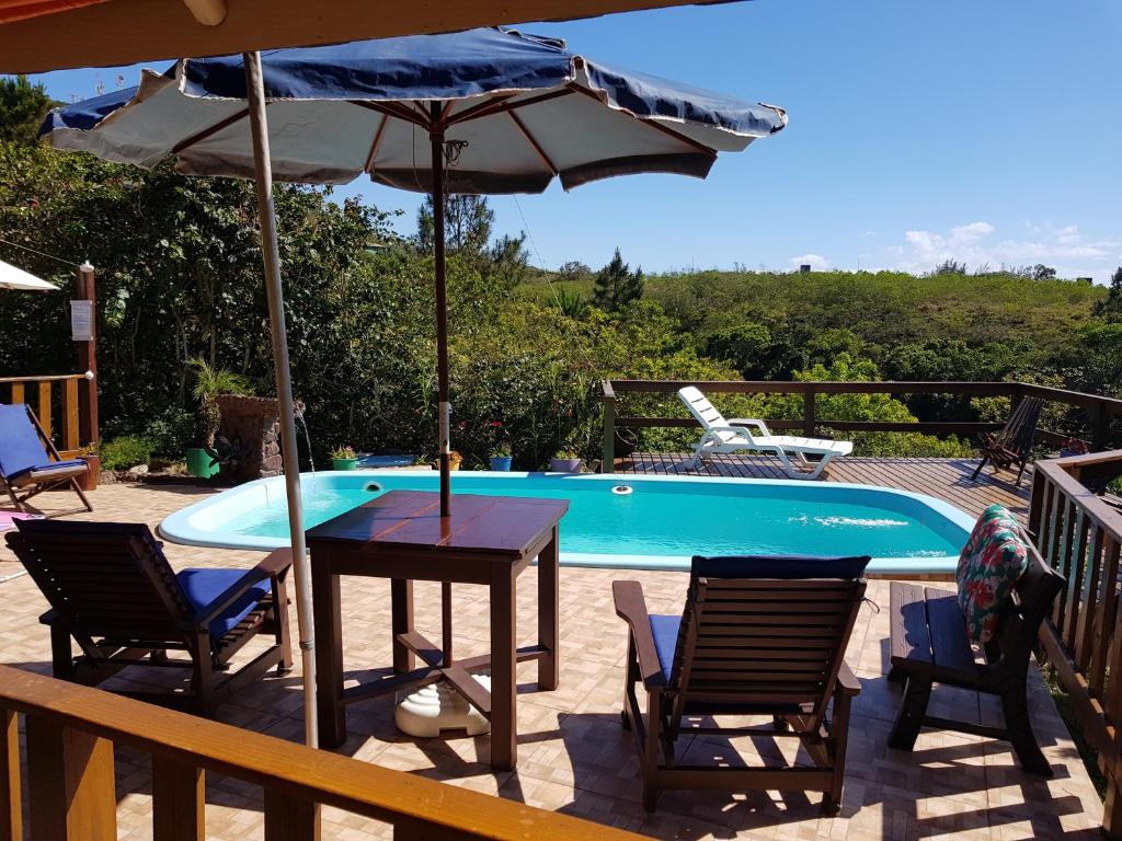 a table with an umbrella next to a swimming pool at Residencial Emery Village in Garopaba