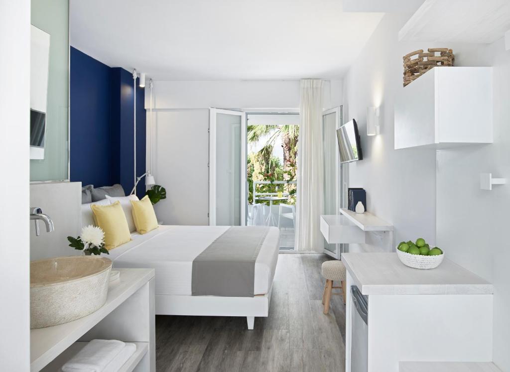 a white bedroom with a sink and a bed at Kouros Seasight Hotel in Pythagoreio